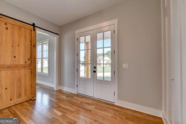 doorway to outside with french doors, light hardwood / wood-style flooring, and a barn door