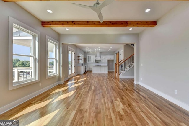 unfurnished living room with ceiling fan, beam ceiling, and light hardwood / wood-style flooring