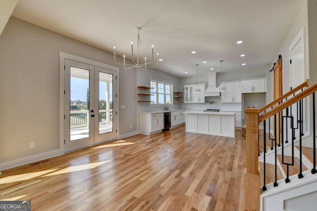 kitchen with a barn door, white cabinetry, custom exhaust hood, and a kitchen island