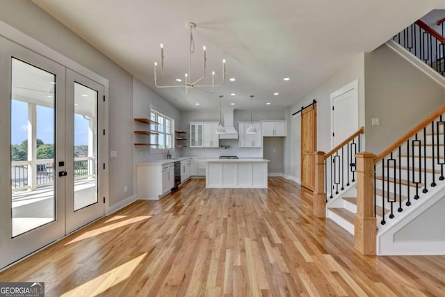 kitchen featuring a barn door, custom range hood, light hardwood / wood-style floors, white cabinets, and a center island