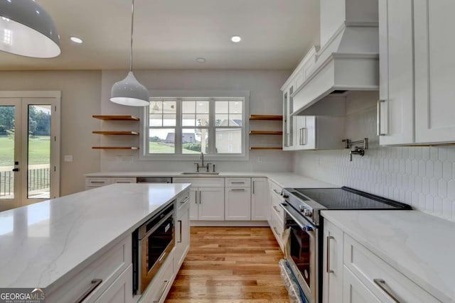 kitchen featuring stainless steel appliances, light stone counters, white cabinets, sink, and light wood-type flooring