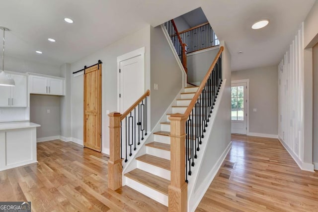 stairway featuring a barn door and hardwood / wood-style flooring