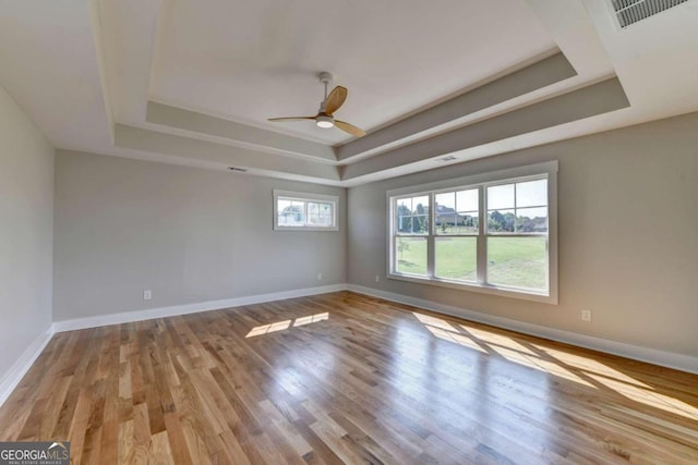 spare room featuring light wood-type flooring, ceiling fan, and a tray ceiling