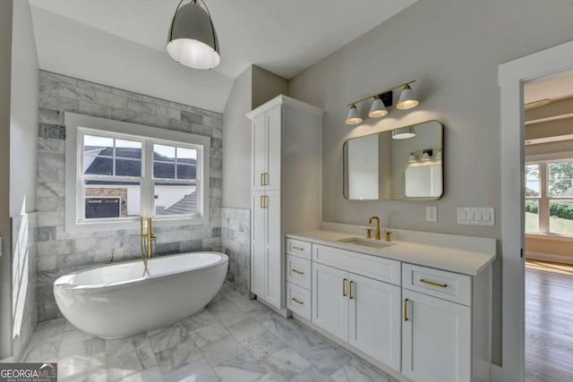 bathroom featuring vanity, a bath, and tile walls