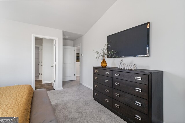 bedroom with light carpet and lofted ceiling