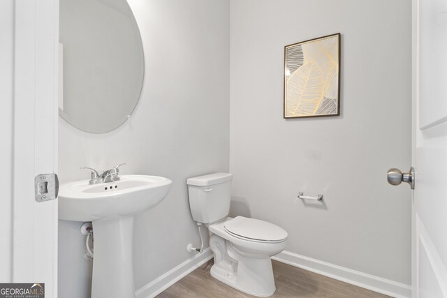 bathroom with hardwood / wood-style flooring, toilet, and sink