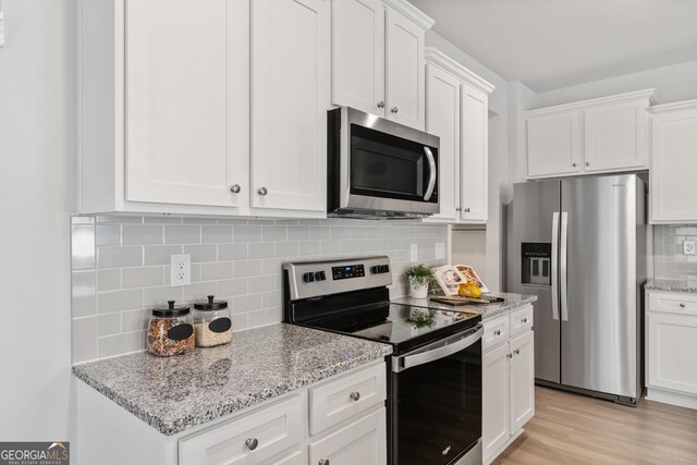 kitchen with tasteful backsplash, white cabinetry, stainless steel appliances, and light hardwood / wood-style floors