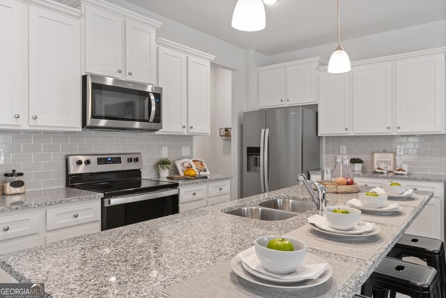 kitchen featuring white cabinetry, sink, hanging light fixtures, tasteful backsplash, and appliances with stainless steel finishes