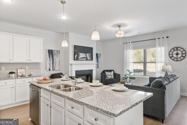 kitchen featuring white cabinets, dishwasher, a center island with sink, and sink