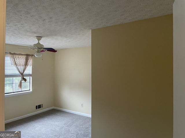 carpeted spare room with ceiling fan and a textured ceiling