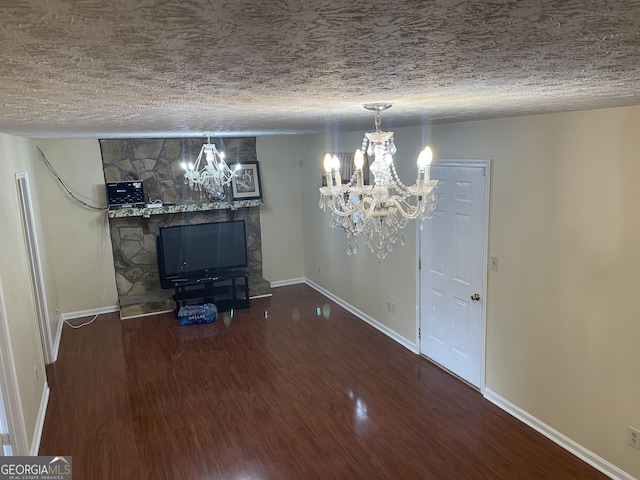 unfurnished dining area with a fireplace, a textured ceiling, dark hardwood / wood-style floors, and a notable chandelier