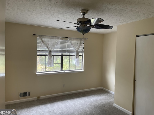 carpeted spare room featuring ceiling fan and a textured ceiling