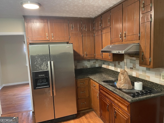 kitchen featuring stainless steel refrigerator with ice dispenser, backsplash, a textured ceiling, black stovetop, and light wood-type flooring