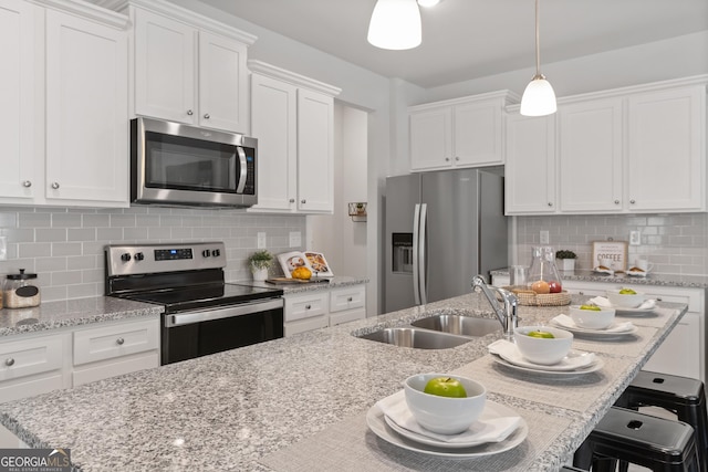 kitchen with white cabinetry, appliances with stainless steel finishes, pendant lighting, and backsplash