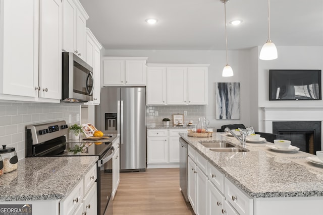 kitchen featuring white cabinetry, sink, decorative light fixtures, and appliances with stainless steel finishes