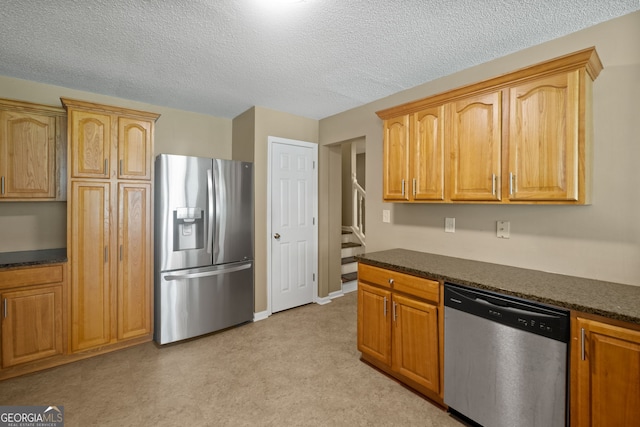 kitchen with stainless steel appliances, a textured ceiling, dark stone counters, and light colored carpet