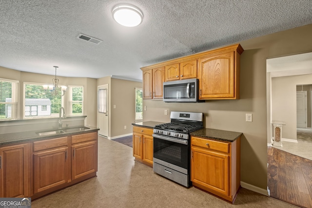 kitchen featuring sink, appliances with stainless steel finishes, a textured ceiling, and a chandelier