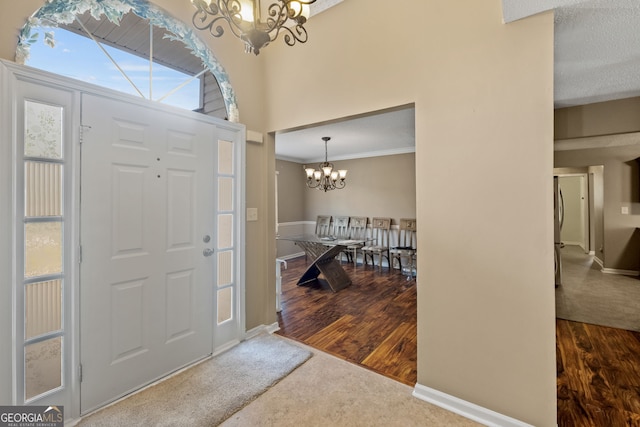 foyer entrance featuring a textured ceiling, ornamental molding, an inviting chandelier, and hardwood / wood-style floors