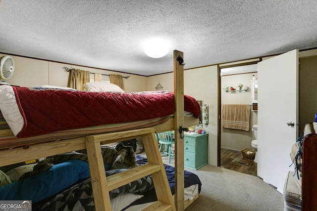 bedroom with a textured ceiling, wood-type flooring, and ensuite bath