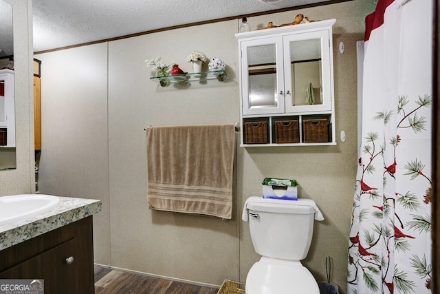 bathroom featuring crown molding, oversized vanity, a textured ceiling, hardwood / wood-style flooring, and toilet