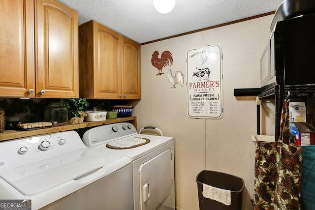 washroom featuring cabinets, a textured ceiling, ornamental molding, and washing machine and clothes dryer