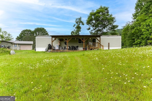 rear view of property featuring an outdoor structure and a lawn