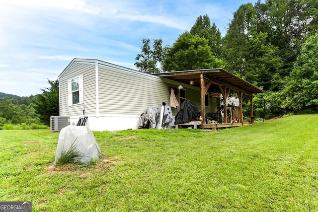 rear view of house featuring central AC unit and a yard