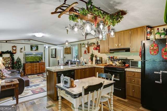 kitchen featuring hanging light fixtures, sink, black appliances, and hardwood / wood-style flooring