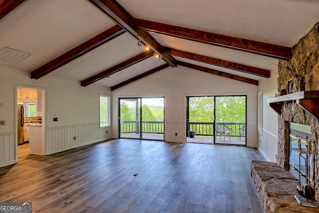 unfurnished living room featuring hardwood / wood-style flooring, a stone fireplace, and lofted ceiling with beams