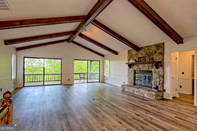 unfurnished living room with vaulted ceiling with beams, a stone fireplace, and wood-type flooring