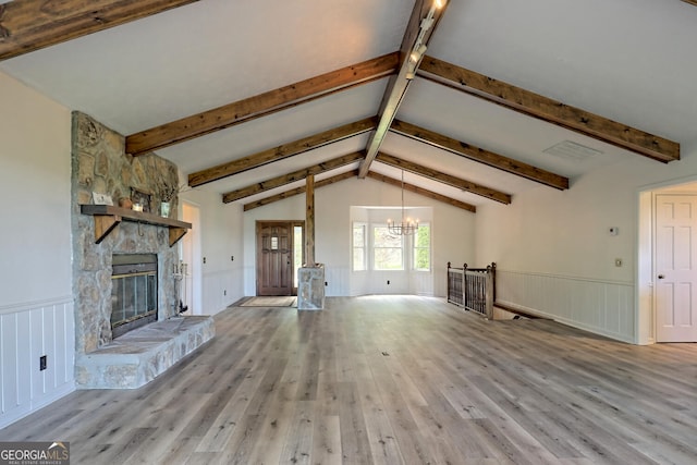 unfurnished living room featuring lofted ceiling with beams, a chandelier, a fireplace, and light wood-type flooring