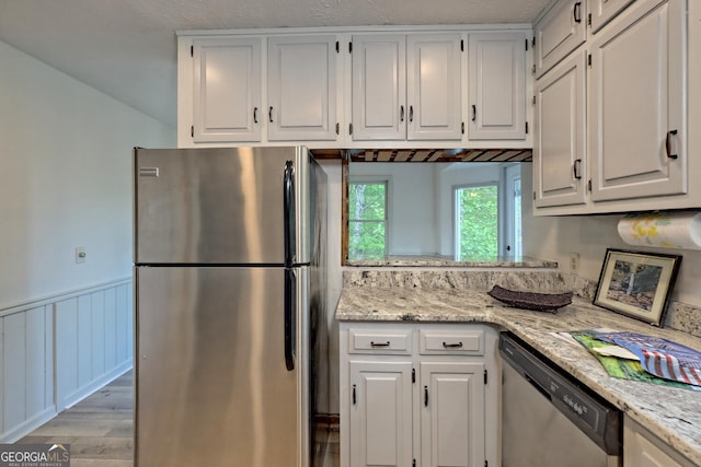 kitchen featuring white cabinetry, light hardwood / wood-style flooring, light stone countertops, and appliances with stainless steel finishes