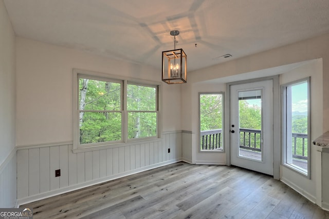 spare room featuring a chandelier and light hardwood / wood-style flooring