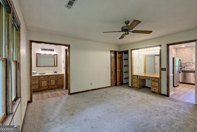 unfurnished bedroom with stainless steel refrigerator, ceiling fan, connected bathroom, and light carpet