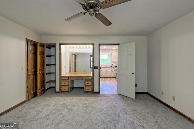 unfurnished bedroom with connected bathroom, light colored carpet, and ceiling fan