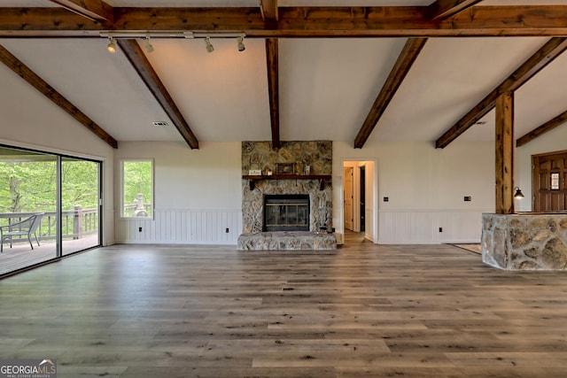 unfurnished living room with a fireplace, wood-type flooring, lofted ceiling with beams, and track lighting