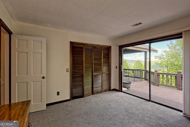 unfurnished bedroom featuring light colored carpet, access to exterior, and a closet