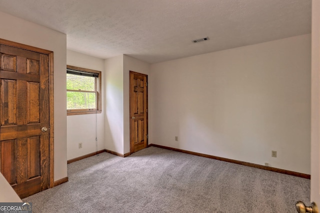 unfurnished bedroom with light colored carpet and a textured ceiling