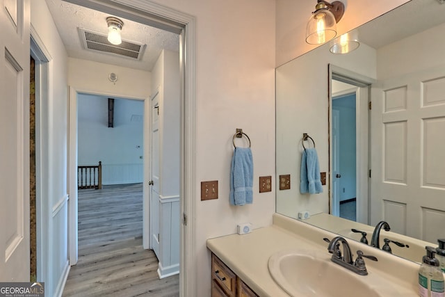 bathroom with wood-type flooring, vanity, and a textured ceiling