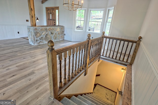 stairs with hardwood / wood-style flooring and a notable chandelier