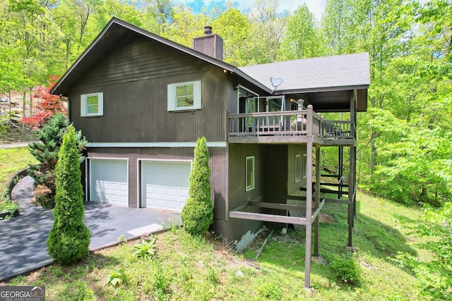 rear view of property featuring a garage, a lawn, and a deck