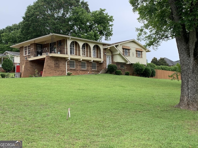 view of front of property featuring a balcony and a front yard