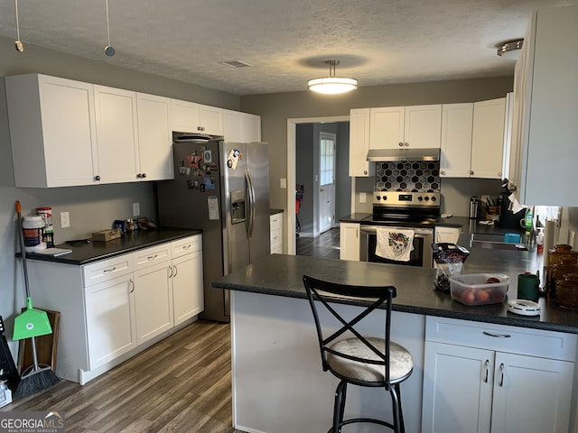 kitchen featuring a kitchen breakfast bar, dark hardwood / wood-style flooring, a textured ceiling, stainless steel appliances, and white cabinets