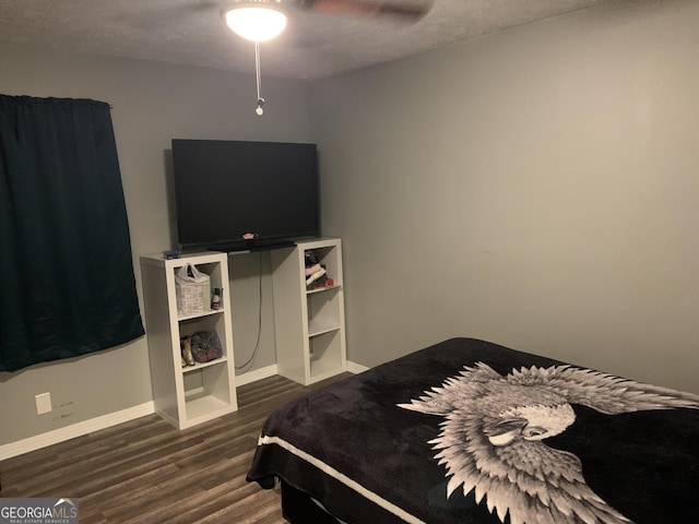 bedroom featuring dark hardwood / wood-style floors, ceiling fan, and a textured ceiling