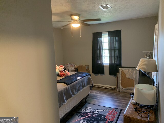 bedroom with dark hardwood / wood-style floors and a textured ceiling