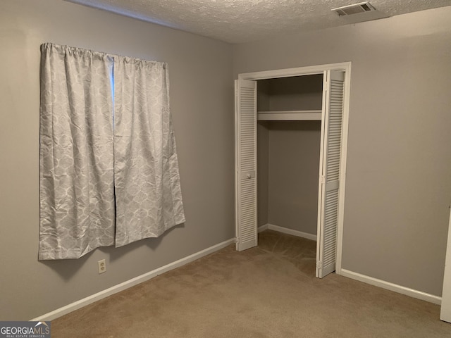 unfurnished bedroom featuring a textured ceiling, carpet floors, and a closet