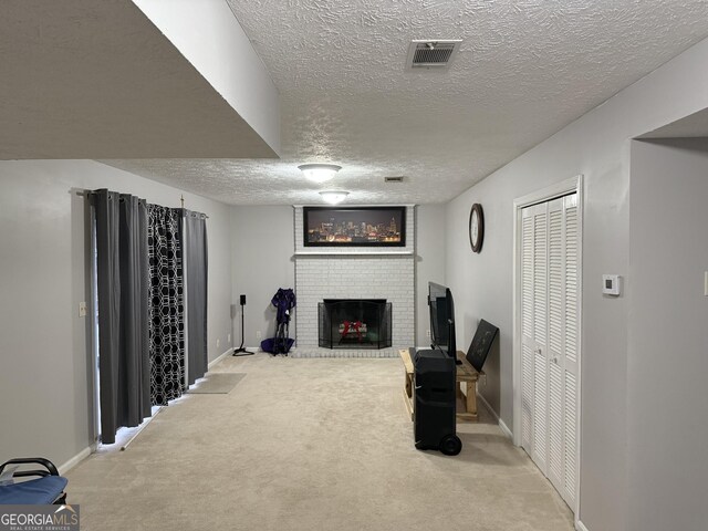 unfurnished living room with a textured ceiling, carpet floors, and a brick fireplace