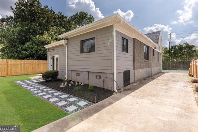 view of side of home with a lawn and a patio area