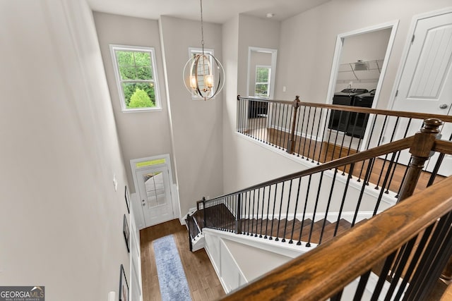 staircase featuring washer and dryer, wood-type flooring, and a chandelier