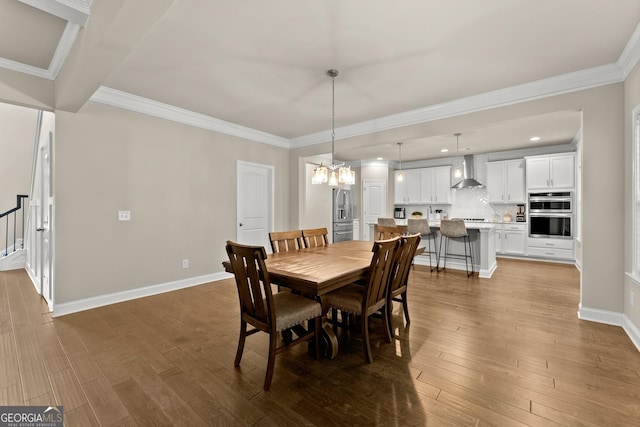 dining space featuring wood-type flooring, ornamental molding, and a chandelier